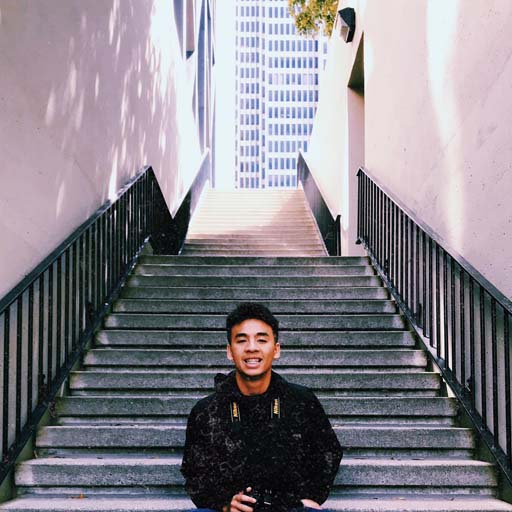 Khanh smiling while sitting on some stairs