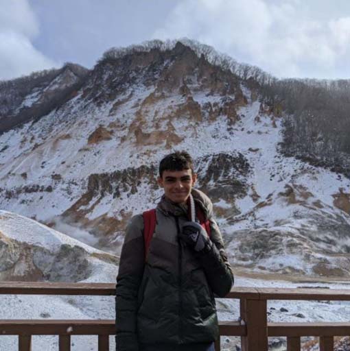 Samarth smiling while standing in front of a mountain